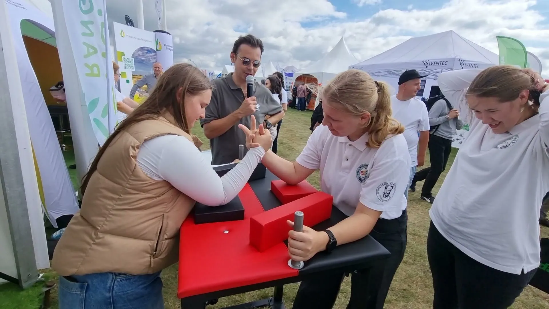 Konferansjer z mikrofonem prowadzi konkurs siłowania na rękę na stoisku TotalEnergies podczas Agro Show 2025
