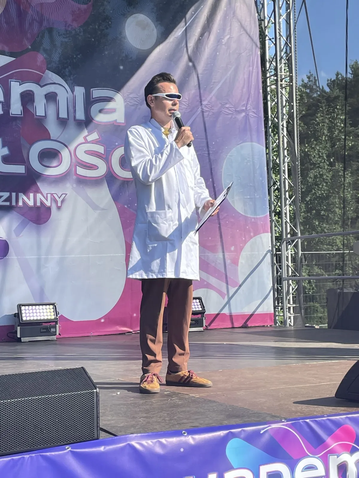 Konferansjer w fartuchu naukowca i futurystycznych okularach zapowiada punkt programu na scenie pikniku Akademia Przyszłości