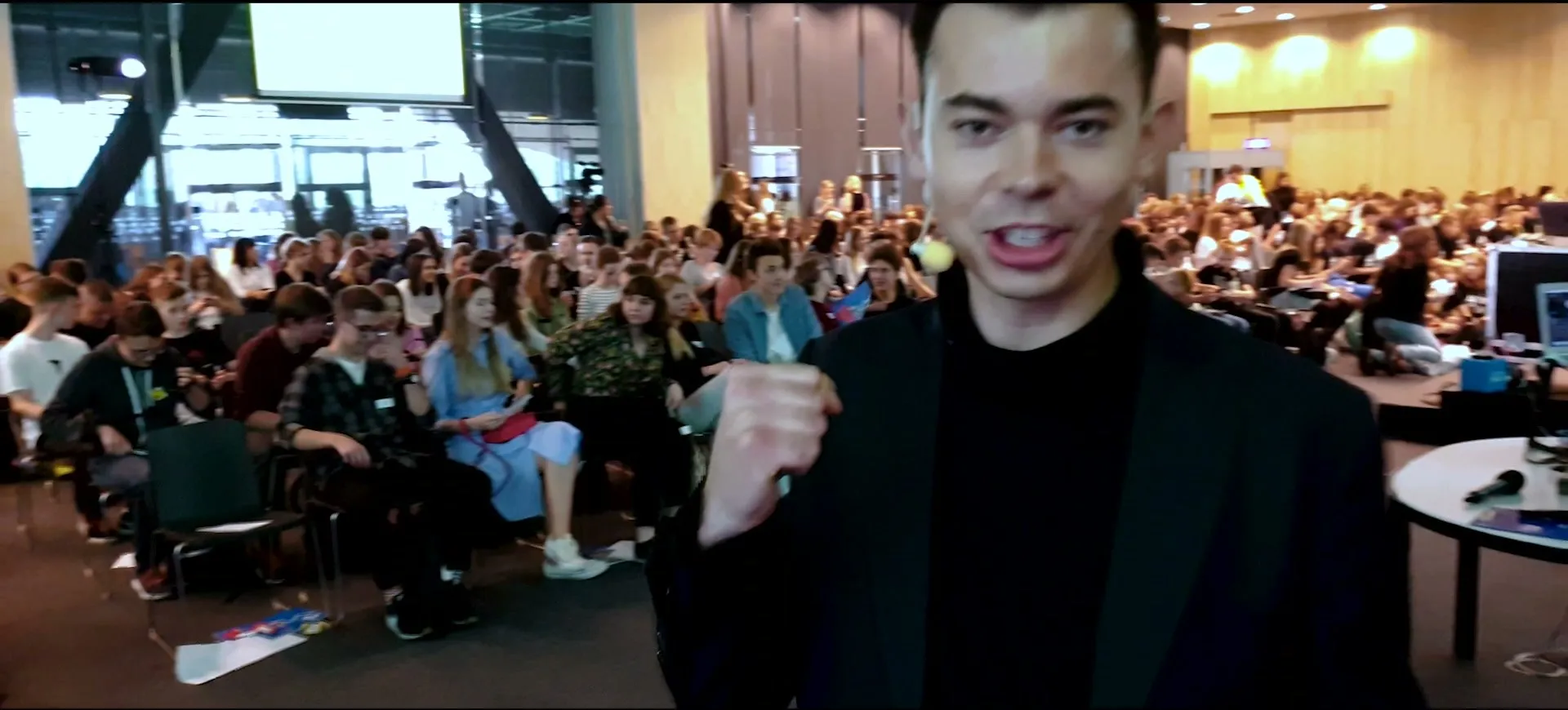 Szymon Alaba z mikrofonem nagłownym na tle pełnej widowni Digital Youth Forum 2019