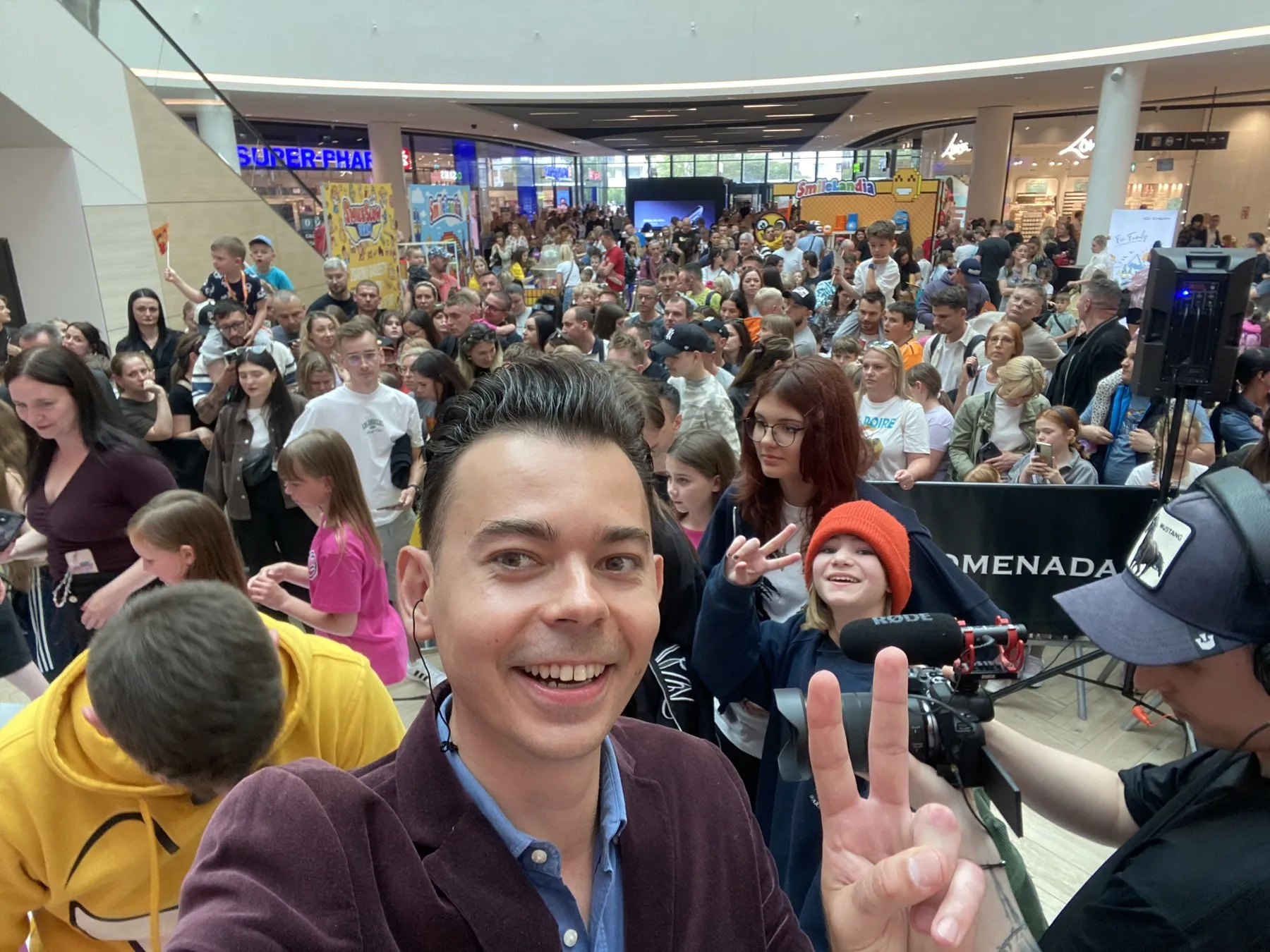 Konferansjer Szymon Alaba na tle tłumu fanów SmileSlow i kamery w G City Promenada