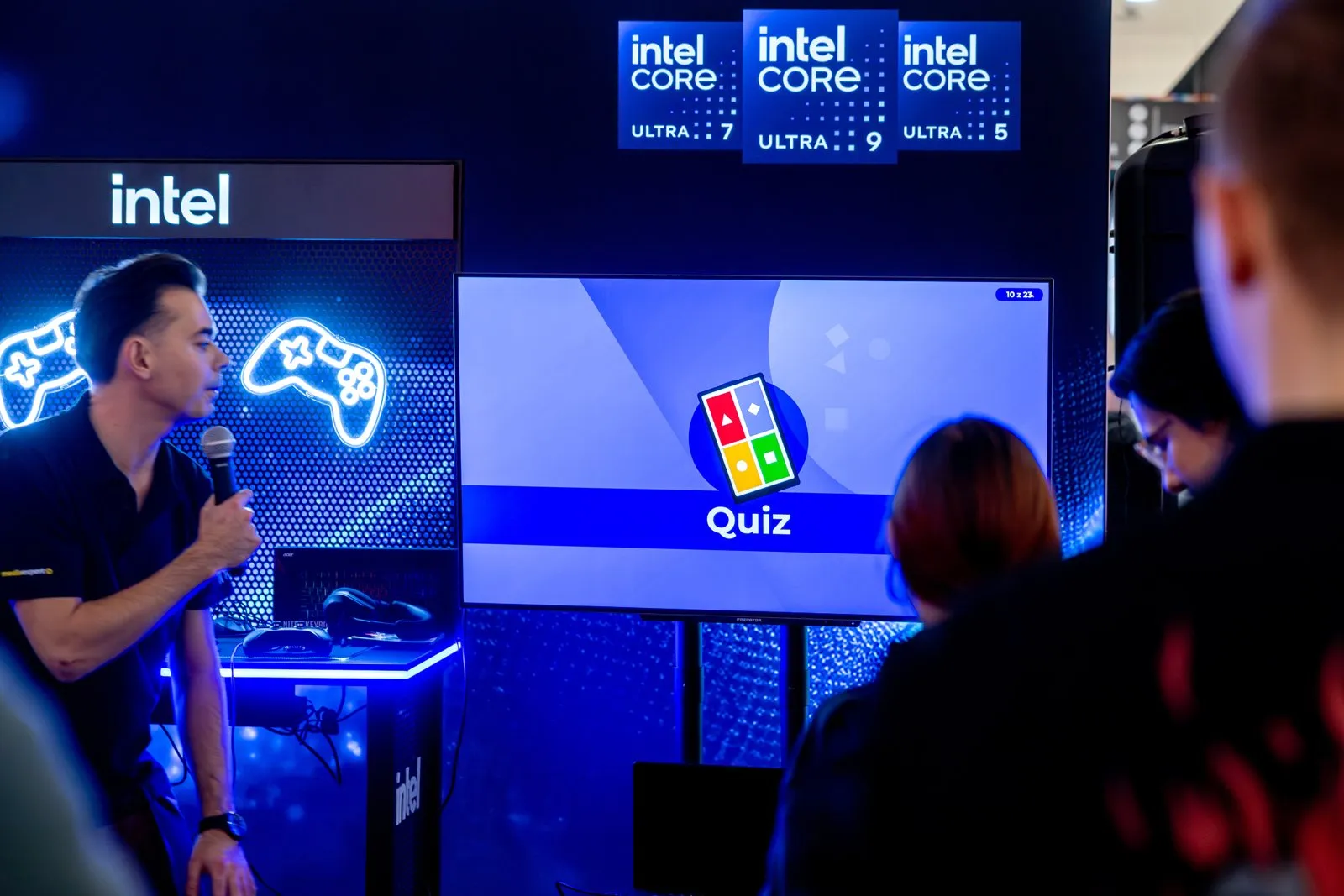 Prowadzący z mikrofonem przy ekranie z quizem w strefie Intel Gamer Arena w łódzkiej Nowej Sukcesji