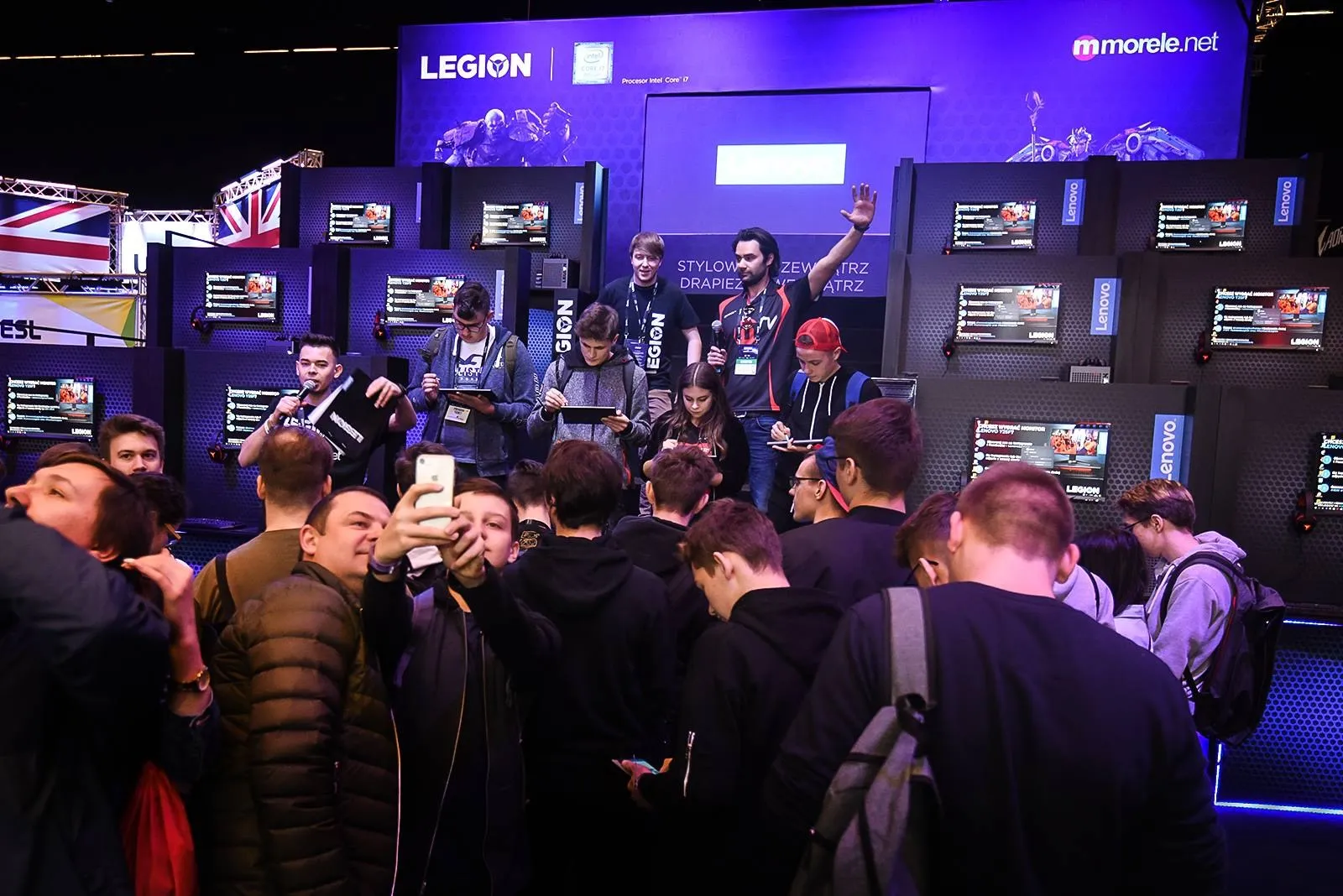 Szymon Alaba prowadzi konkurs na scenie strefy Lenovo Legion na IEM Katowice 2019, przed sceną publiczność