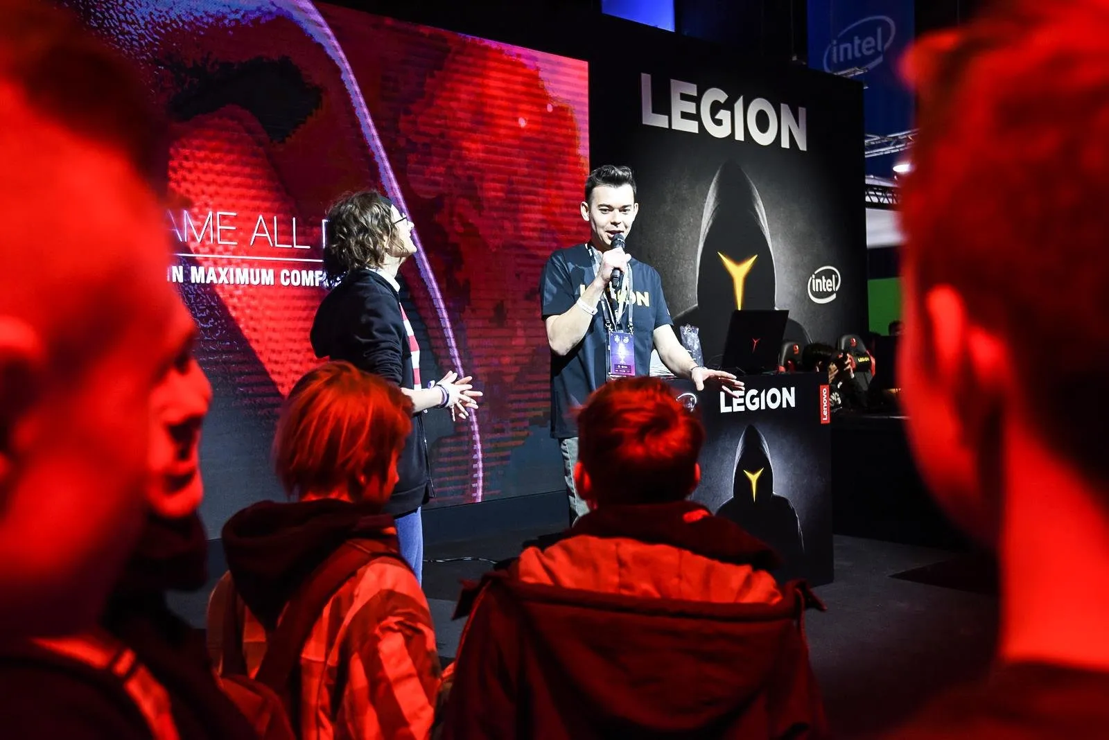 Szymon Alaba z mikrofonem na scenie strefy Lenovo Legion, przed sceną widzowie