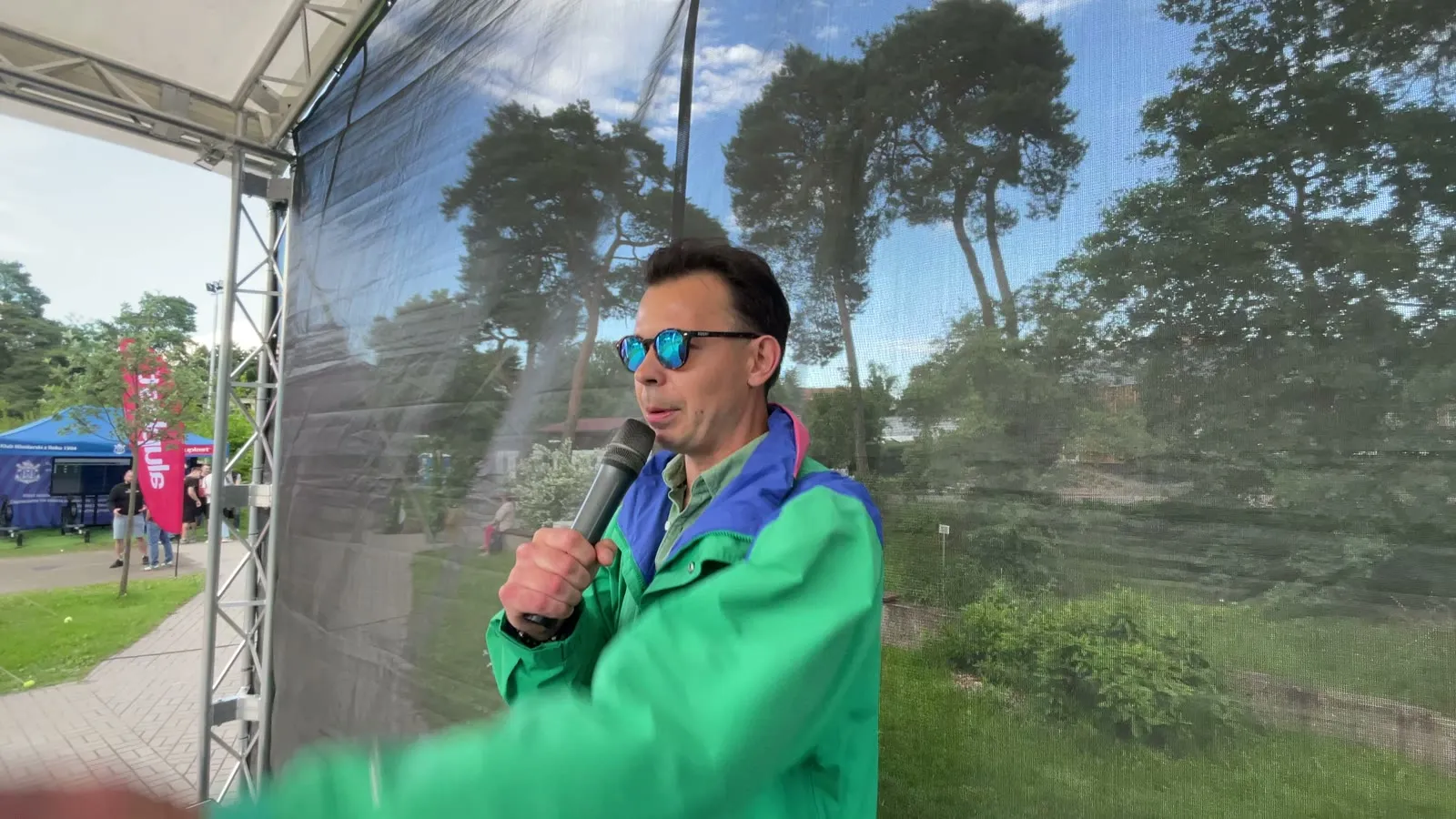 Prowadzący w kolorowej kurtce z mikrofonem na scenie plenerowej pikniku aluplast w Poznaniu