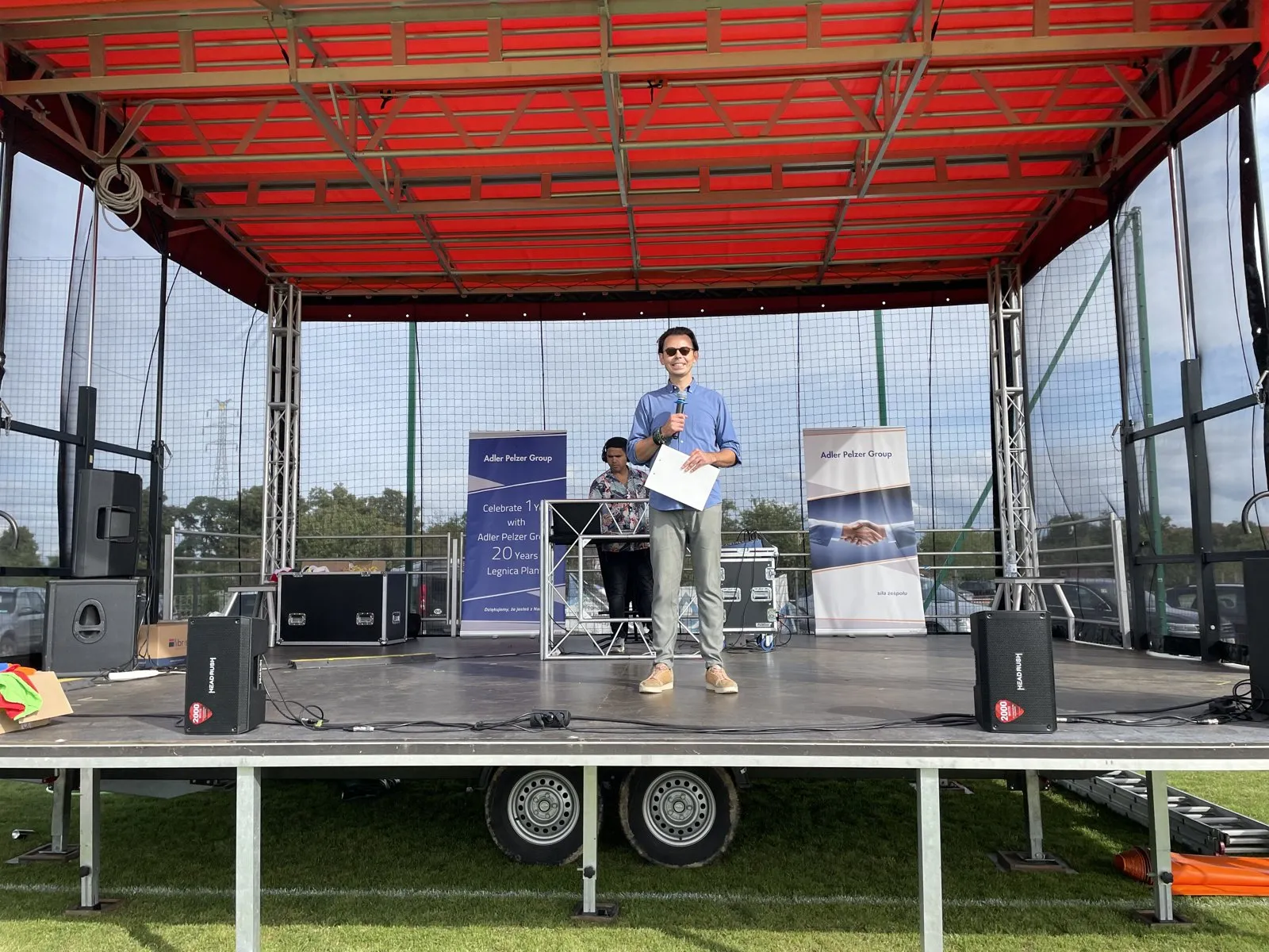 Szymon Alaba na scenie pikniku rodzinnego Adler, w tle banery firmy