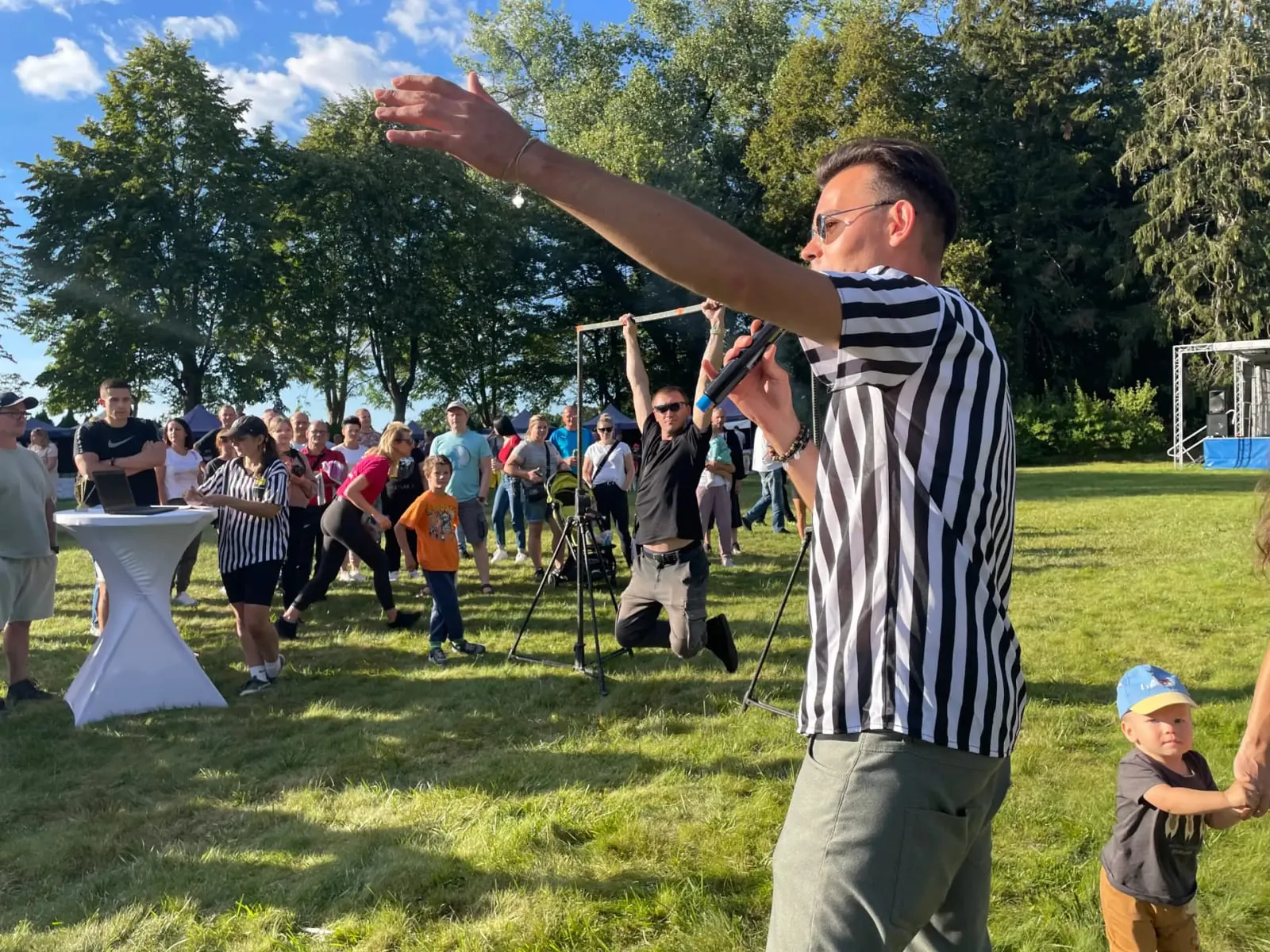 Prowadzący w stroju sędziego z uniesioną ręką na pikniku sportowym