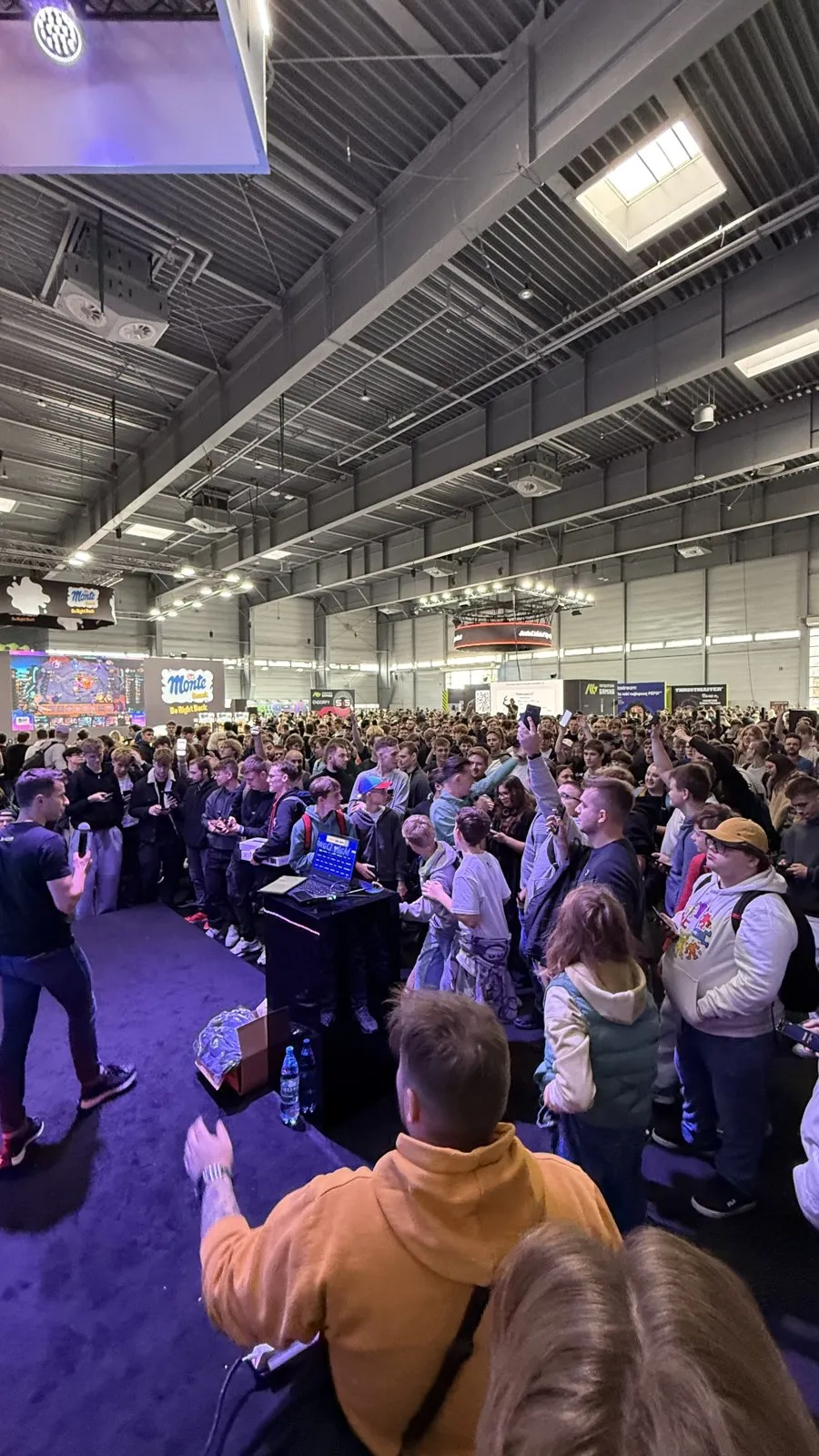 Tłum uczestników przed sceną strefy x-kom w hali Międzynarodowych Targów Poznańskich, Poznań Game Arena 2025